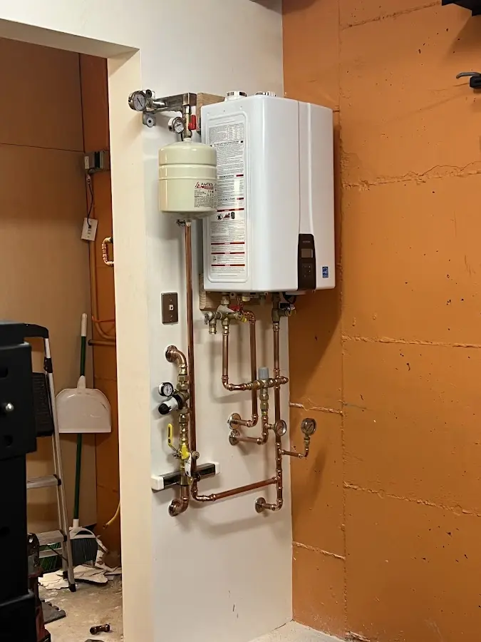 Plumbing technician inspecting water heater connections in Perkins